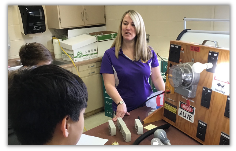 Local utility guest speaker showing a water meter display to high school students