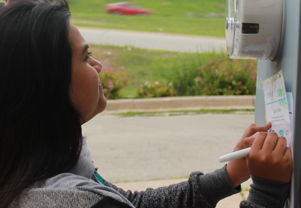 Student reads her home electricity meter and writes down the numbers for a class project